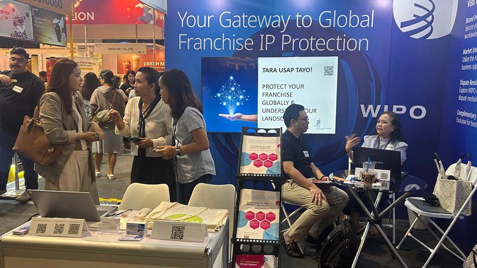  WIPO booth at a franchise expo featuring a banner reading "Your Gateway to Global Franchise IP Protection," with attendees and staff interacting at the display.